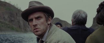 Movie still from “Apostle” (2018), directed by Gareth Evans – A person wearing a hat near a body of water; Close Up shot, Over the shoulder angle