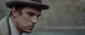 Movie still from “Apostle” (2018), directed by Gareth Evans – A person wearing a hat; Close Up shot, Over the shoulder angle