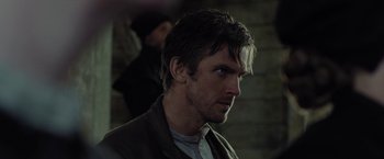 Movie still from “Apostle” (2018), directed by Gareth Evans – A person wearing a jacket; Close Up shot, Over the shoulder angle