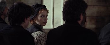 Movie still from “Apostle” (2018), directed by Gareth Evans – A woman in a hat and a dress looking at a man in a suit and tie; Close Up shot, Over the shoulder angle