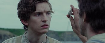 Movie still from “Apostle” (2018), directed by Gareth Evans – A young man holding a snake in his hand; Close Up shot, Low angle