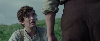 Movie still from “Apostle” (2018), directed by Gareth Evans – A man holding a man's hand while standing in a field; Close Up shot, Over the shoulder angle