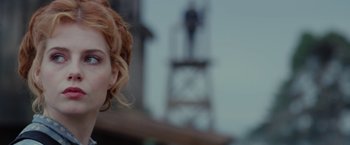Movie still from “Apostle” (2018), directed by Gareth Evans – A woman's face in front of a building; Close Up shot, Over the shoulder angle