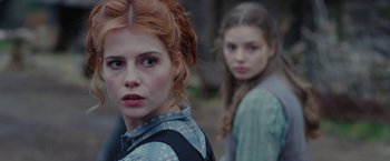 Movie still from “Apostle” (2018), directed by Gareth Evans – Two young women standing next to each other; Close Up shot, Over the shoulder angle