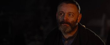 Movie still from “Apostle” (2018), directed by Gareth Evans – A man with a goatee and a beard; Close Up shot, Over the shoulder angle