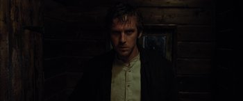 Movie still from “Apostle” (2018), directed by Gareth Evans – A man standing in the dark in front of a window; Close Up shot, Low angle