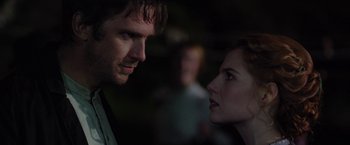 Movie still from “Apostle” (2018), directed by Gareth Evans – A man and a woman face to face in the dark; Close Up shot, Over the shoulder angle