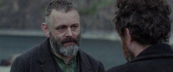 Movie still from “Apostle” (2018), directed by Gareth Evans – A man with a gray beard talking to another man; Close Up shot, Over the shoulder angle