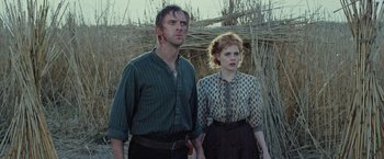 Movie still from “Apostle” (2018), directed by Gareth Evans – A man and a woman standing next to each other; Medium shot, Low angle