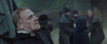 Movie still from “Apostle” (2018), directed by Gareth Evans – A group of men in black hats and coats; Close Up shot, Over the shoulder angle