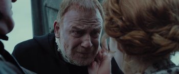 Movie still from “Apostle” (2018), directed by Gareth Evans – An older man looking into a mirror while holding a finger up to his ear; Close Up shot, Over the shoulder angle