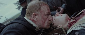 Movie still from “Apostle” (2018), directed by Gareth Evans – A man and a woman kissing each other on the lips; Close Up shot, Over the shoulder angle