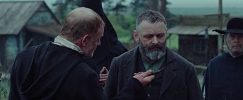 Movie still from “Apostle” (2018), directed by Gareth Evans – A man with a beard is looking at a cell phone; Close Up shot, Over the shoulder angle