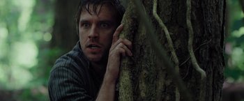 Movie still from “Apostle” (2018), directed by Gareth Evans – A man leaning against a tree with his hand on his face; Close Up shot, Low angle