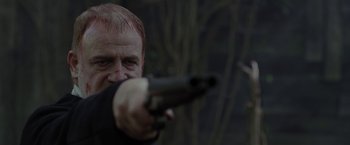 Movie still from “Apostle” (2018), directed by Gareth Evans – A man is holding a gun in his hand; Close Up shot, Over the shoulder angle