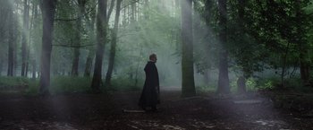 Movie still from “Apostle” (2018), directed by Gareth Evans – A man in a black robe walking through the woods; Wide shot, Low angle