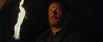 Movie still from “Apostle” (2018), directed by Gareth Evans – A person wearing a black shirt; Close Up shot, Low angle