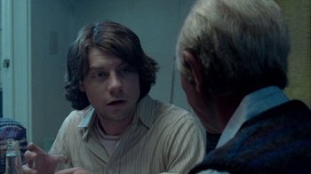 A man talking to another man in front of a mirror