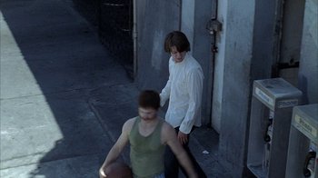 Movie still from “Wristcutters: A Love Story” (2006), directed by Goran Dukic – A young man sitting on the ground next to a young woman; Wide shot, High angle