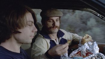 Two men sitting in the back of a car eating food