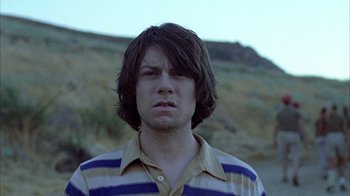 A man with long brown hair wearing a striped shirt