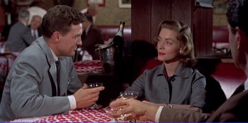 Movie still from “Written on the Wind” (1956), directed by Douglas Sirk – A man and a woman sitting at a table with wine glasses in front of them; Medium shot, Over the shoulder angle