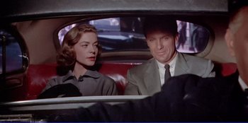 Movie still from “Written on the Wind” (1956), directed by Douglas Sirk – A man and a woman sitting in the back of a car; Medium shot, Over the shoulder angle