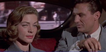 Movie still from “Written on the Wind” (1956), directed by Douglas Sirk – A man and a woman sitting in the back of a car; Close Up shot, Over the shoulder angle