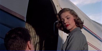 Movie still from “Written on the Wind” (1956), directed by Douglas Sirk – A woman with red lipstick standing in front of an airplane door; Close Up shot, Low angle