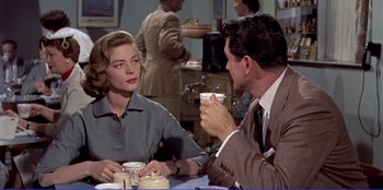 Movie still from “Written on the Wind” (1956), directed by Douglas Sirk – A man and a woman sitting at a table with a cup; Medium shot, Over the shoulder angle
