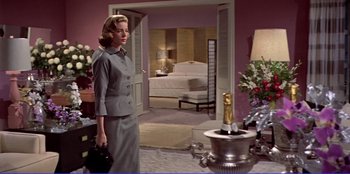 Movie still from “Written on the Wind” (1956), directed by Douglas Sirk – A woman standing in front of a champagne bottle; Medium shot, Low angle