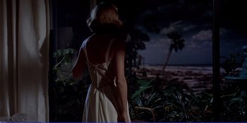 Movie still from “Written on the Wind” (1956), directed by Douglas Sirk – A woman in a white dress standing in front of palm trees; Wide shot, Low angle