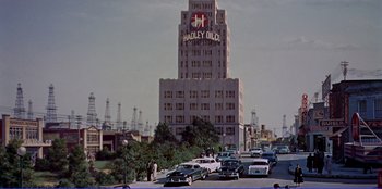Movie still from “Written on the Wind” (1956), directed by Douglas Sirk – A tall building with a clock on the top of it; Extreme Wide shot, Low angle