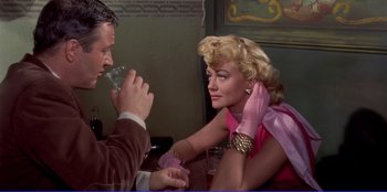 Movie still from “Written on the Wind” (1956), directed by Douglas Sirk – A man and a woman sitting at a table with a glass; Medium shot, Over the shoulder angle