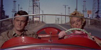 Movie still from “Written on the Wind” (1956), directed by Douglas Sirk – A man and a woman riding in an old fashioned car; Medium shot, Low angle