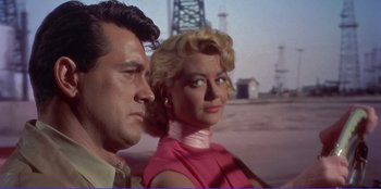 Movie still from “Written on the Wind” (1956), directed by Douglas Sirk – A man and a woman standing next to each other in front of an oil rig; Close Up shot, Low angle