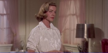 Movie still from “Written on the Wind” (1956), directed by Douglas Sirk – A woman in a white dress standing next to a window; Medium shot, Low angle