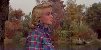 Movie still from “Written on the Wind” (1956), directed by Douglas Sirk – A woman with blonde hair wearing a plaid shirt; Medium shot, Low angle