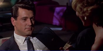 Movie still from “Written on the Wind” (1956), directed by Douglas Sirk – A man in a suit and tie talking to a woman in a suit and tie; Close Up shot, Over the shoulder angle