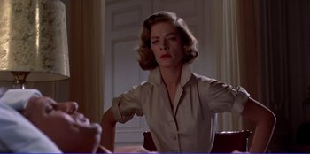 Movie still from “Written on the Wind” (1956), directed by Douglas Sirk – A woman sitting at a table in front of a window; Medium shot, Low angle
