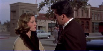 Movie still from “Written on the Wind” (1956), directed by Douglas Sirk – A man and a woman talking to each other on the street; Medium shot, Over the shoulder angle