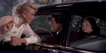 Movie still from “Written on the Wind” (1956), directed by Douglas Sirk – A man and a woman sitting in the back seat of a car; Medium shot, Over the shoulder angle