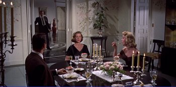 Movie still from “Written on the Wind” (1956), directed by Douglas Sirk – A group of people sitting around a dinner table; Medium shot, Over the shoulder angle