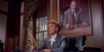 Movie still from “Written on the Wind” (1956), directed by Douglas Sirk – A woman sitting in front of a picture of a man; Medium shot, Low angle