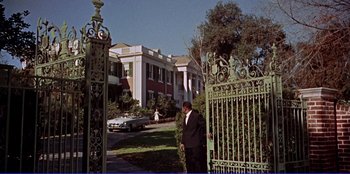 Movie still from “Written on the Wind” (1956), directed by Douglas Sirk – A man standing in front of an iron gate; Extreme Wide shot, Low angle