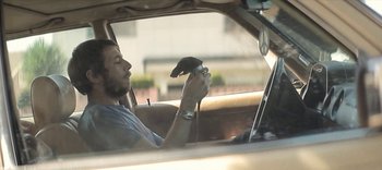 Movie still from “Wrong Cops” (2013), directed by Quentin Dupieux – A man sitting in the driver's seat of a car; Close Up shot, Low angle
