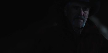 Movie still from “Yellowstone” (2018), created by John Linson – A man with a beard is standing in the dark; Close Up shot, Low angle