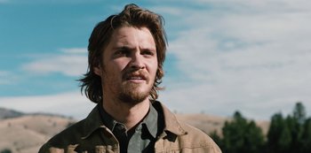 Movie still from “Yellowstone” (2018), created by John Linson – A person with long hair and a beard; Close Up shot, Over the shoulder angle