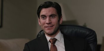 Movie still from “Yellowstone” (2018), created by John Linson – A person wearing a suit and tie; Close Up shot, High angle