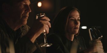 Movie still from “Yellowstone” (2018), created by John Linson – A woman sitting next to a man holding a wine glass; Close Up shot, Over the shoulder angle